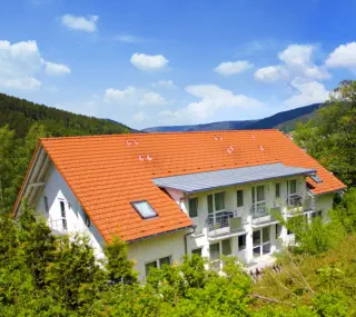 Rückansicht von Haus 1 mit Balkonen und Terrasse im schönen Grün.