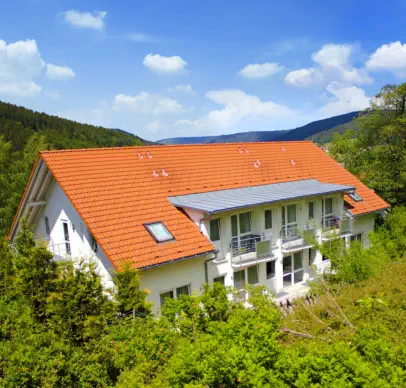 Rückansicht von Haus 1 mit Balkonen und Terrasse im schönen Grün.